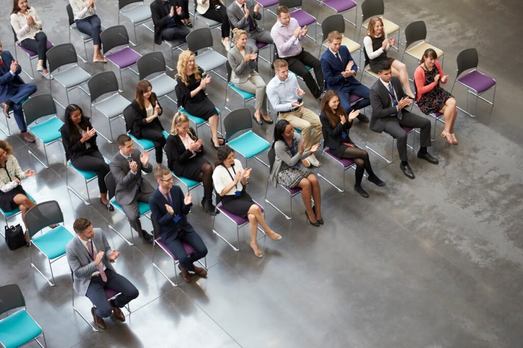 Overhead View Of Audience Applauding Speaker At Conference