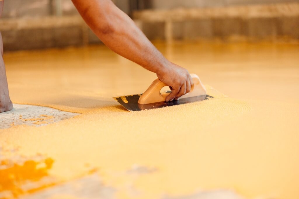 Construction worker spreading self-leveling compound on the floor
