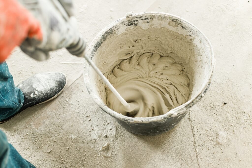 Worker mixing gypsum plaster with water for plastering walls