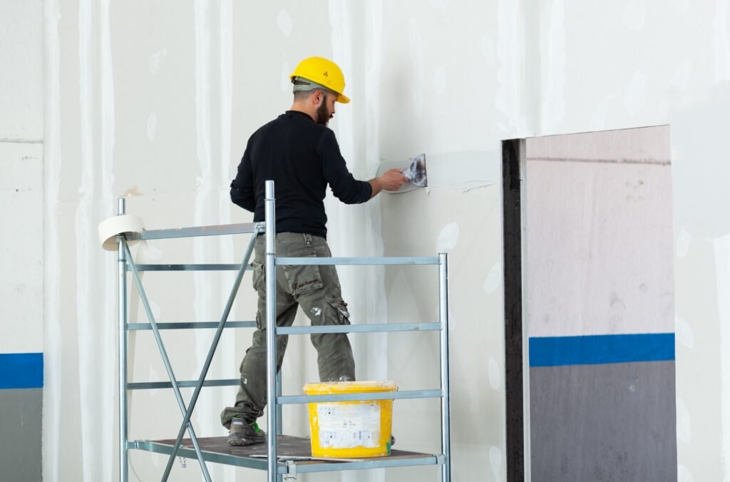 worker plastering gypsum board wall.